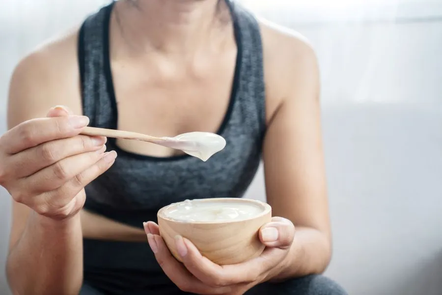 A woman eating yogurt after going to the gym.
